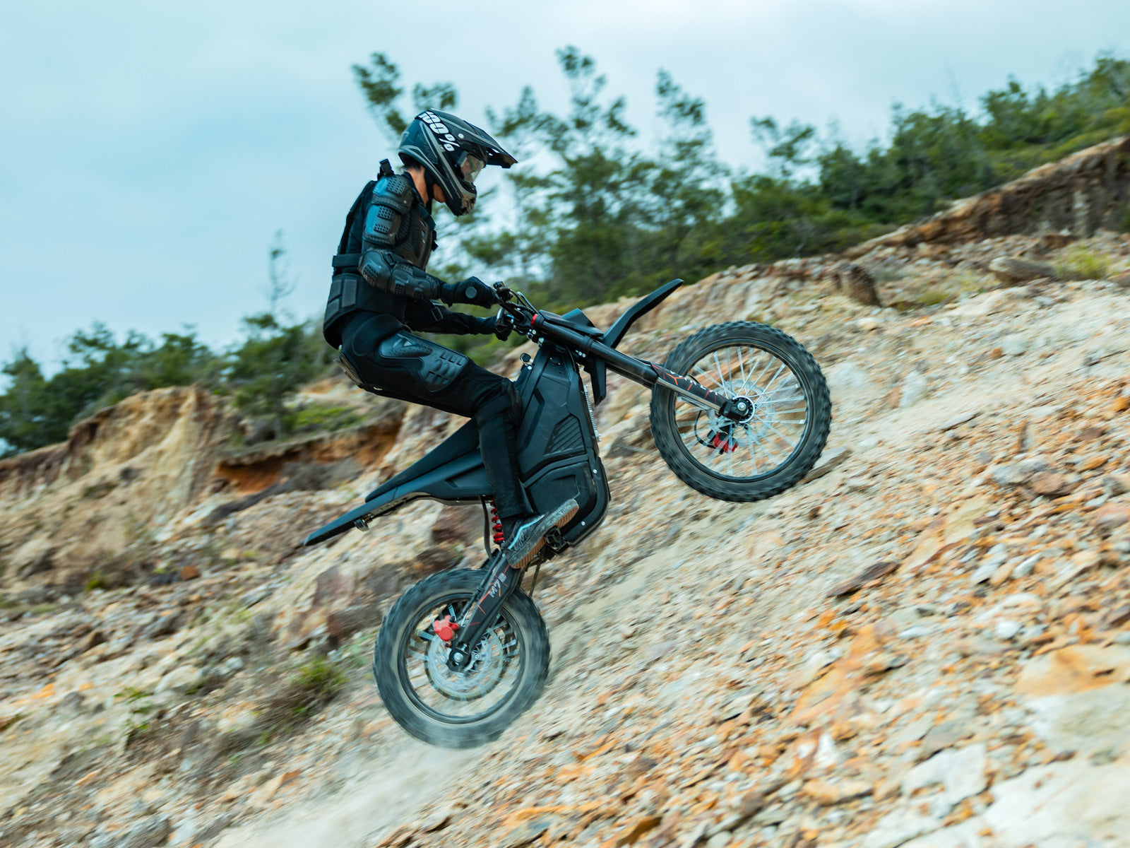 Rider jumping a Varla M7S electric dirt bike on a coastal trail